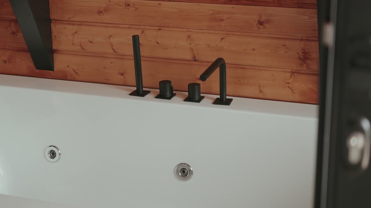 sleek black bathtub faucet and knobs on wood wall background