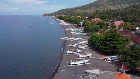 Volcanic-black-sand-Beachfront-of-Amed,-a-fishing-Village-north-of-Bali-Island---Indonesia,-Aerial