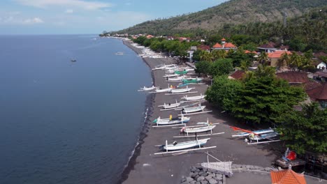 volcanic black sand beachfront of amed, a fishing village north of bali island - indonesia, aerial