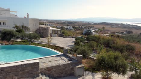 Aerial Orbit of Healthy Woman Leaving the Pool with Paros Landscape View