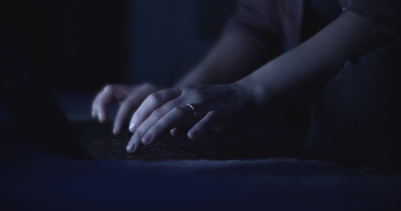 Mani che digitano su una tastiera di notte