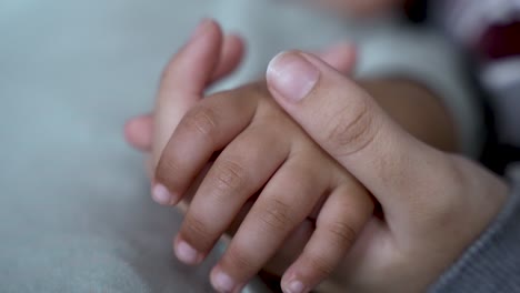 mother gently holds the hand of a young child using thumb to stroke skin