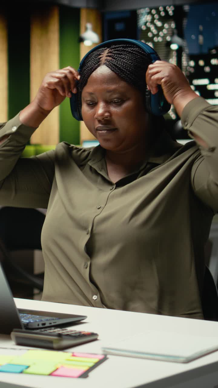 Vertical Video Black woman listening to focus music on headphones at the office