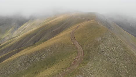 drone video into the clouds gravel dirt road hills foggy mountain gramos peaks