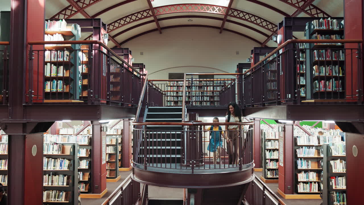 Woman and Child Walk Up a Grand Staircase in a Multi-Story Library
