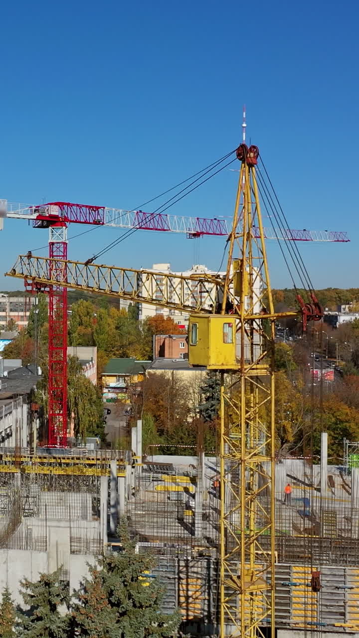 Construction of a new shopping center. Urban background and two cranes on construction site. Video shooting with drone. Vertical video