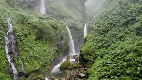 toma aérea de una idílica escena natural mientras unas pocas cataratas se sumergen en el barranco de la jungla