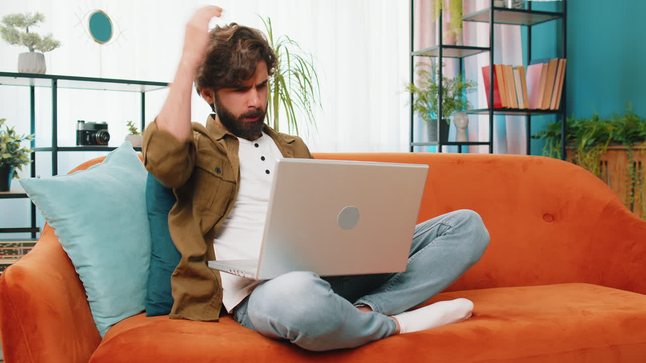 중동의 젊은 남자가 노트북을 사용합니다. 나쁜 소식에 놀랐고, 재산을 잃었습니다. 집에서 복권 결과를 실패했습니다.