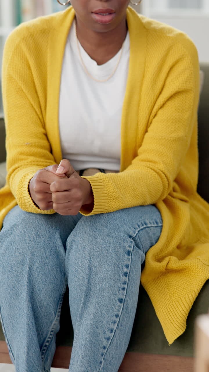 En kvinde sidder i en terapisession, med foldede hænder og kigger ned, og viser tegn på nervøsitet eller angst