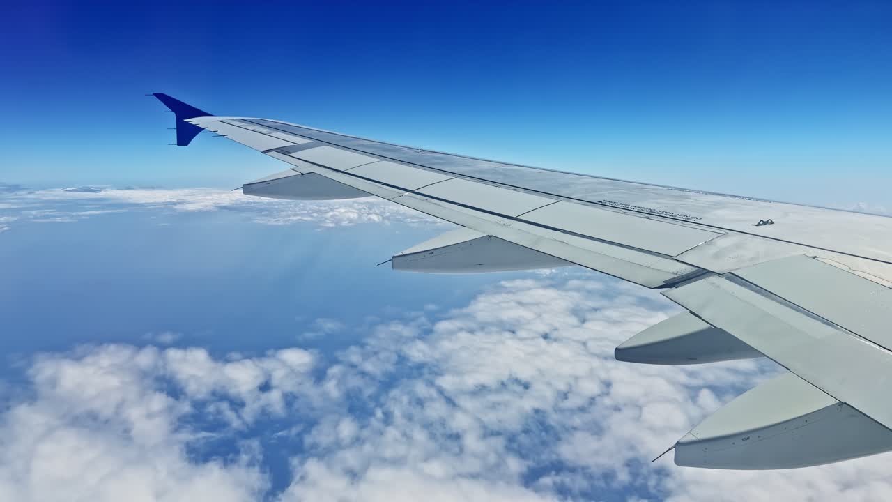 Airplane wing over clouds, clear sky, travel concept, serene atmosphere