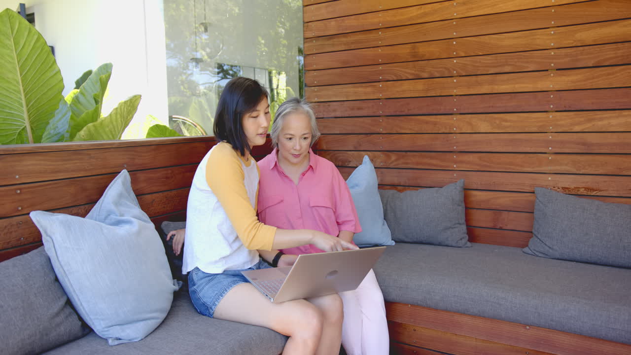 Using laptop, young asian woman and senior asian woman discussing something on screen