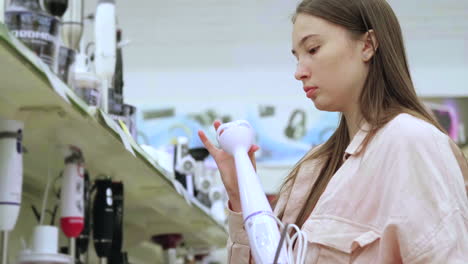 woman shopping for a handheld blender in an electronics store