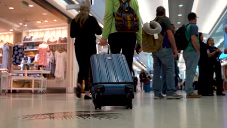 Las-Piernas-Y-El-Equipaje-De-Una-Mujer-Mientras-Camina-Por-Un-Aeropuerto-Concurrido