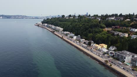 Drone-shot-revealing-the-city-of-Seattle,-along-with-skyscrapers-and-the-Space-Needle,-from-behind-a-hill-in-the-suburbs-of-Alki