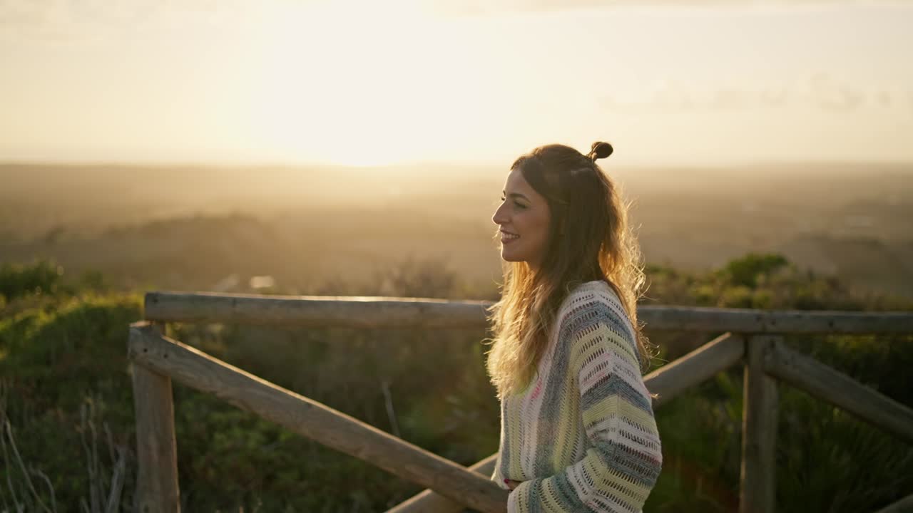 Slow motion shot of a model walking across a wooden bridge and smiling at sunset
