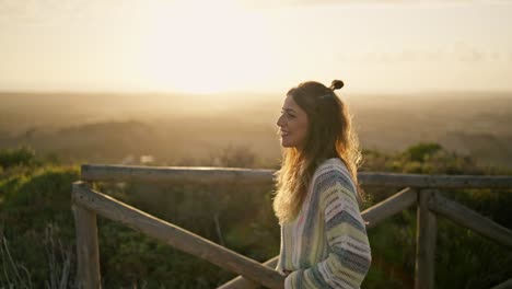 slow motion shot of a model walking across a wooden bridge and smiling at sunset