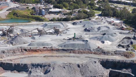 drone footage captures active mining operations at a gold coast quarry, showcasing machinery, trucks, and excavators under bright daylight