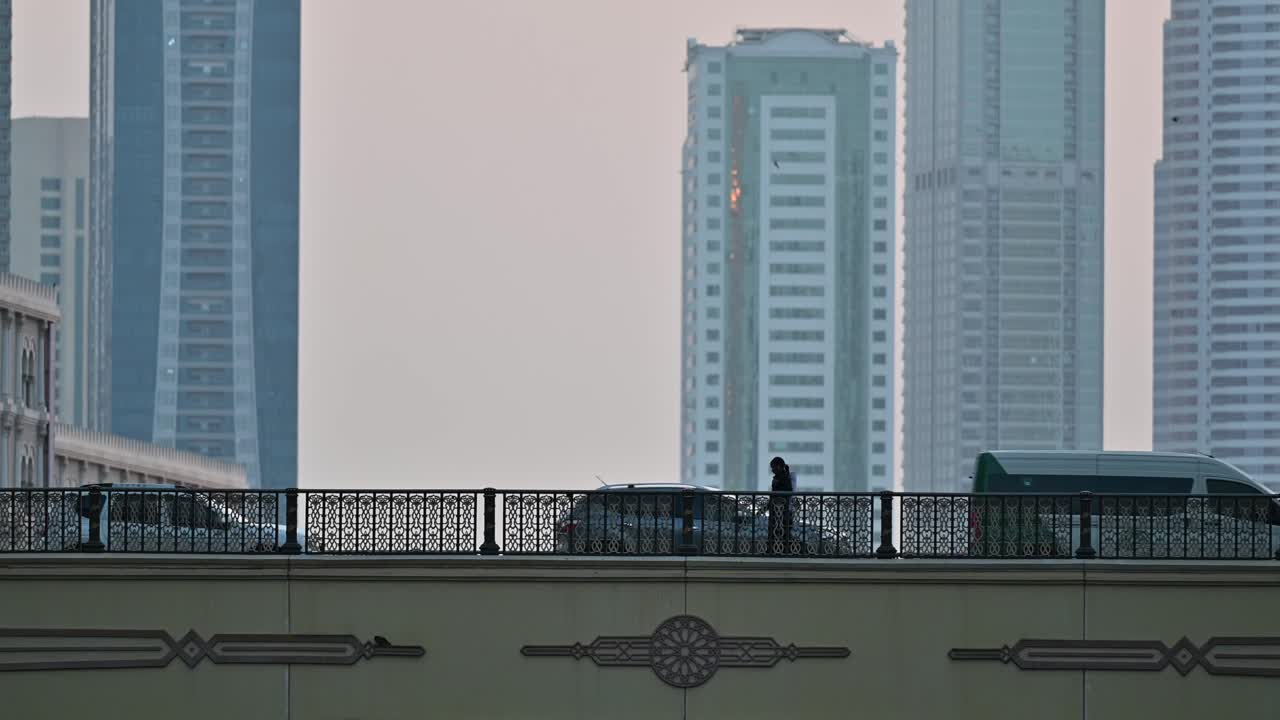 4k: 다리에서  ⁇ 는 여인, 도시 교통과 배경에는 현대적인 주거 타워가 있습니다.