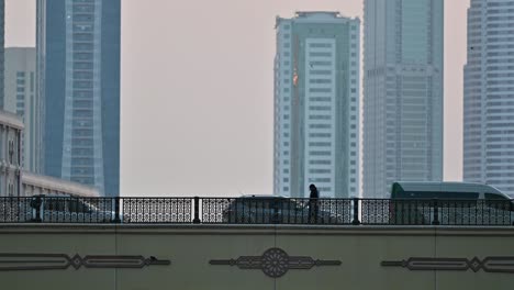 4k: a lady walking on the bridge, city traffic and modern residential towers in the background