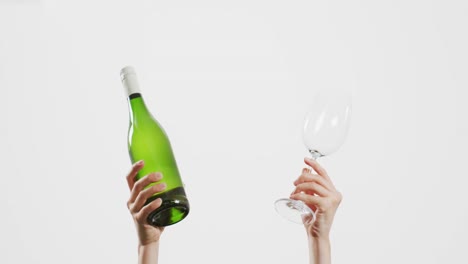 hands of caucasian woman holding bottle of white wine and empty glass with copy space