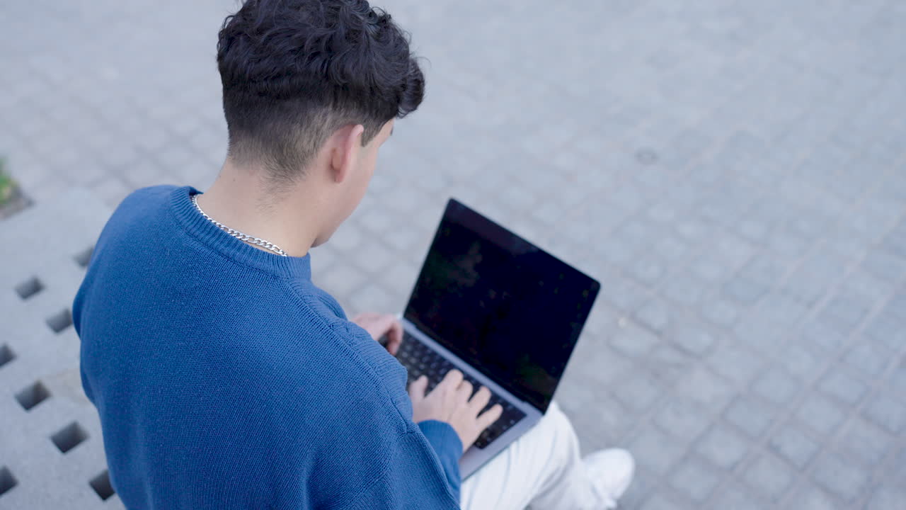 Young male using netbook on street