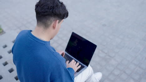 young male using netbook on street