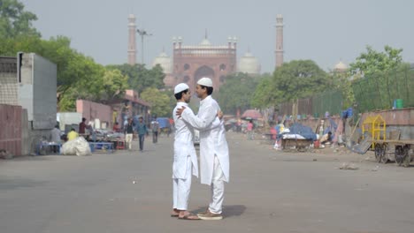 two indian muslim men hugging each other on eid festival in front of jama masjid delhi