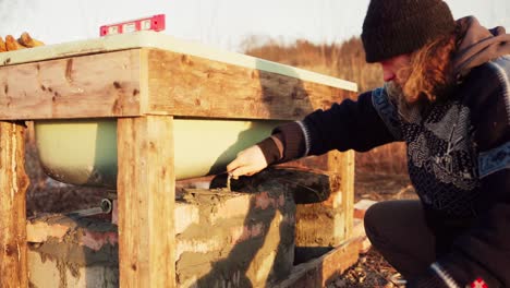 the man checks if the bricks fit properly before cementing them underneath the diy hot tub - timelapse