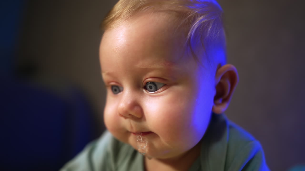 Adorable face of a little baby with big eyes and blond hair. Close up portrait with cute plump cheeks. Close up.
