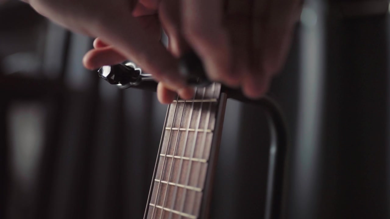 Close-up of an acoustic guitar neck on a stand in a dimly lit room with a soft focus background