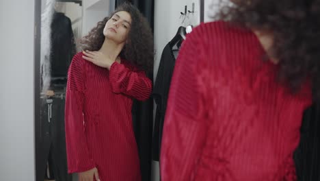 woman trying on a red dress in a fitting room