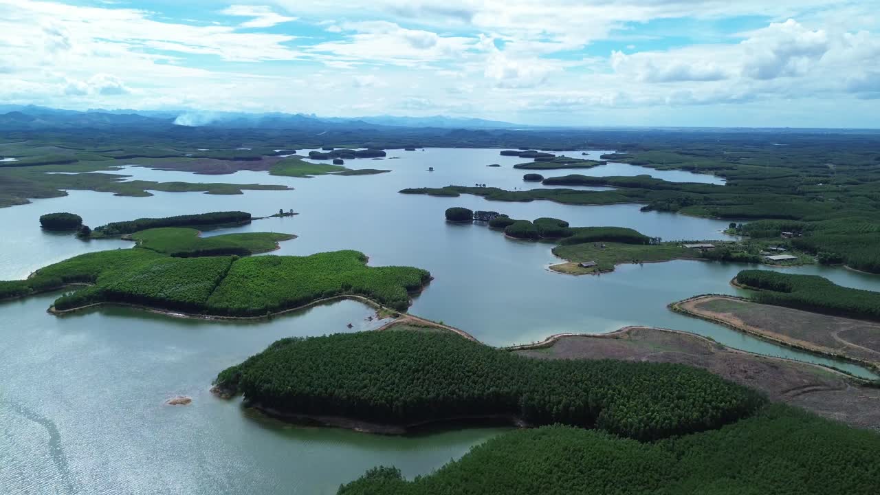 Zoom in ascending over tree-covered islands surrounded by lake water in Vietnam