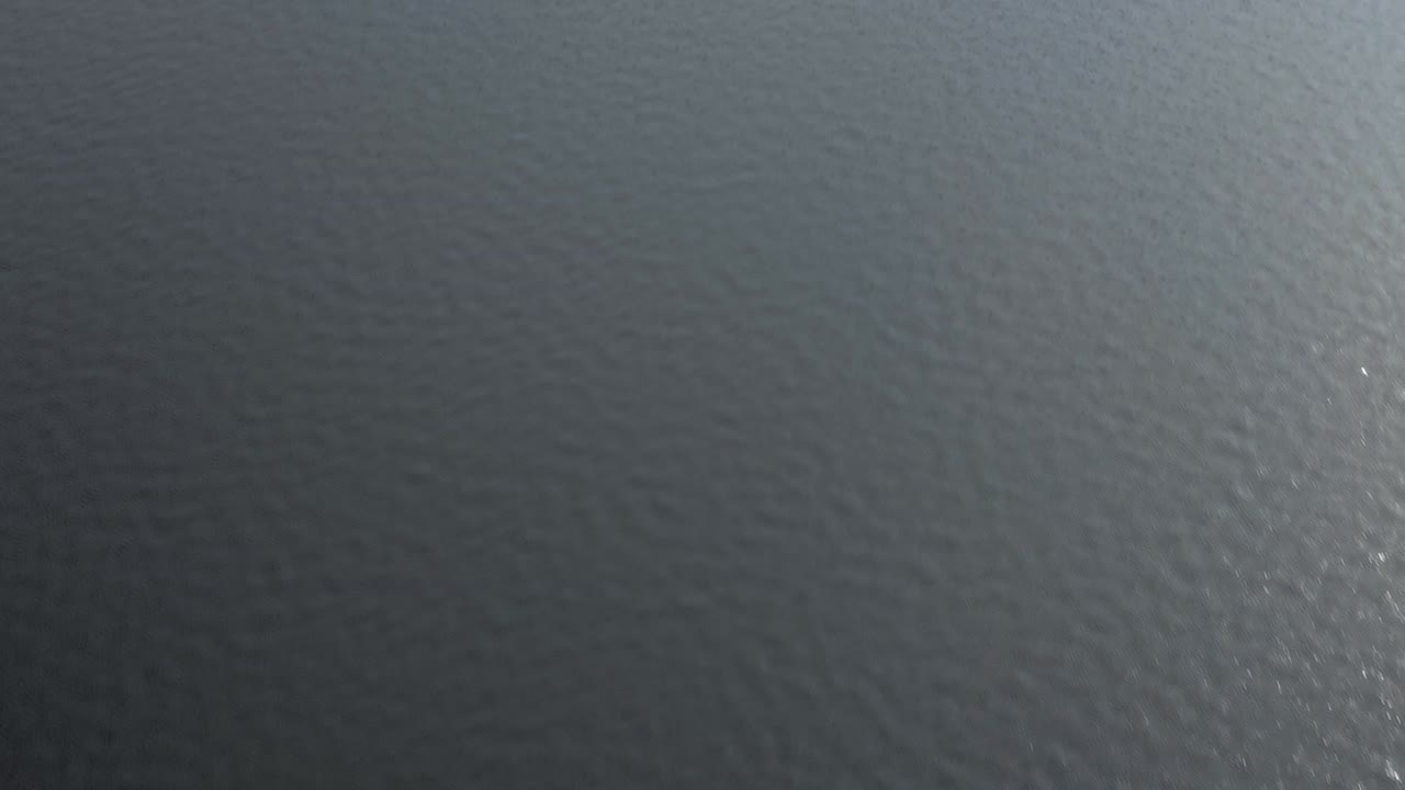 Skimming down towards the surface of a rippling lake with a drone