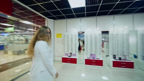 young model posing in new eyeglasses. beautiful woman comes enchantingly wearing fashionable glasses into the optical store.
