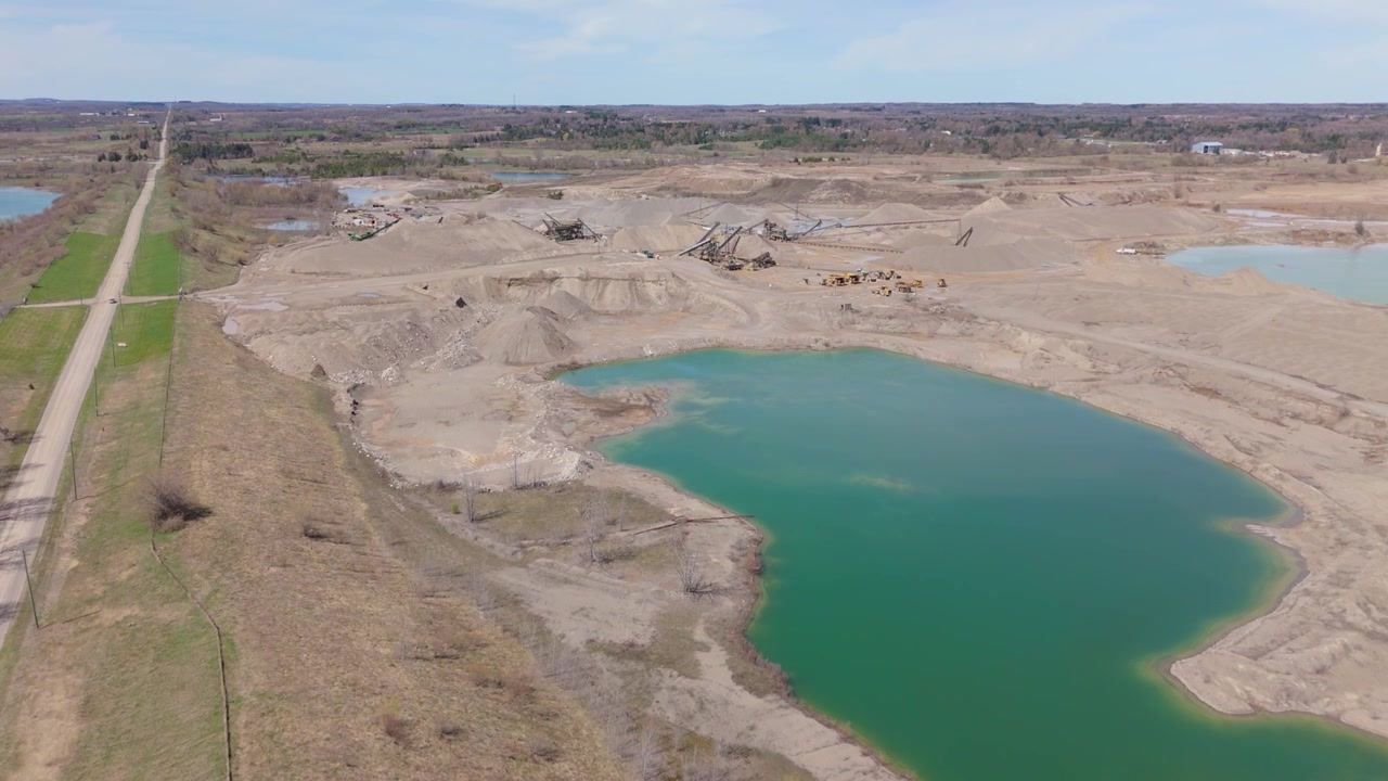 Calm Quarry Lake With A Gravel Spit In The Background Near Caledon Village, Ontario, Canada. Aerial Drone Shot