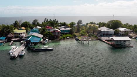 Luftbild-Drohnenlandschaft-Mit-Inselhäusern,-Docks-Im-Karibischen-Meer-In-Utila,-Honduras,-Blaue-Skyline-Bei-Sonnigem-Tageslicht,-Buchthotels