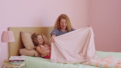 mother and daughter playing peek-a-boo in bed
