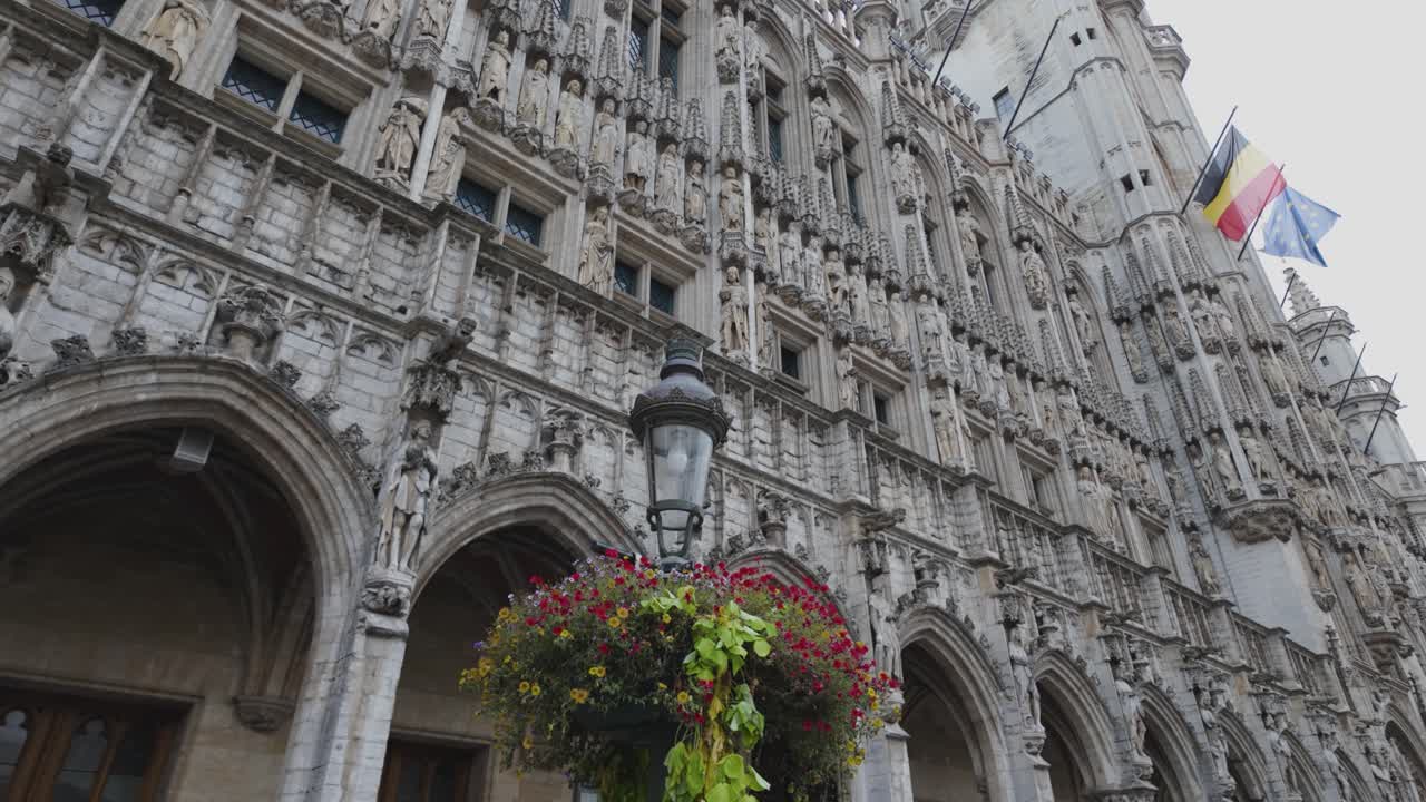 A grand, ornate Brussels Town Hall exterior with flags and floral decor on display