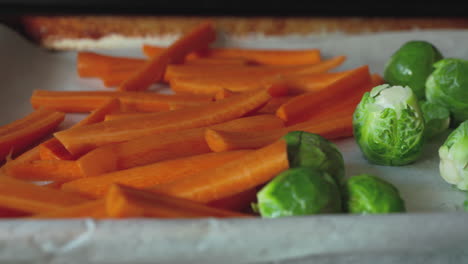 pan across brussels sprouts and carrots on a roasting pan