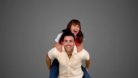hombre sonriente dando a su amigo una mochila en el fondo gris
