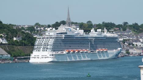 large cruise ship docked at cobh promenade in ireland, with cathedral tower being the only thing standing taller then ship