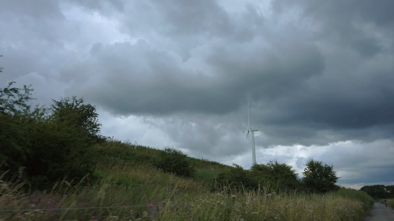 Tracking shot of turning wind turbine on cloudy day