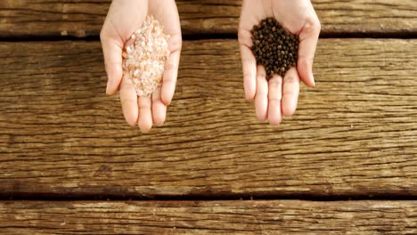 hands of woman holding rock salt and black paper over wooden platform 4k