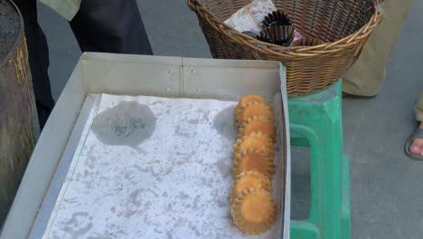 man’s hand quickly lining traditional thai cupcakes on tray and removing paper cups