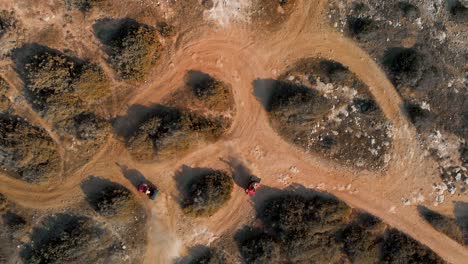 wide aerial shot looking down on two atv dune buggies as they enter frame and race around the tracks in cavo greko