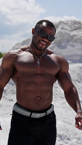 full length view of the strong muscle man walking outdoor with naked torso. shirtless guy on a background of sandy landscapes. vertical video