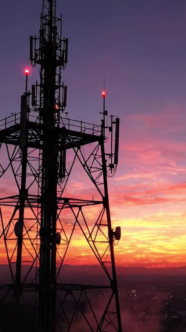 Uno straordinario spettacolo di tecnologia contro un tramonto vibrante: la silhouette di una torre di telecomunicazioni illuminata dal cielo serale.