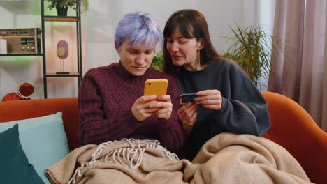 Lesbian-married-women-using-credit-bank-card-and-smartphone-while-transferring-money-online-shopping