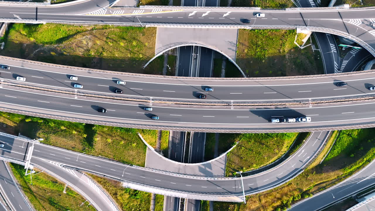Descending above the complicated road system. Cars move quickly by the conjunction with highways and freeways. Top view.