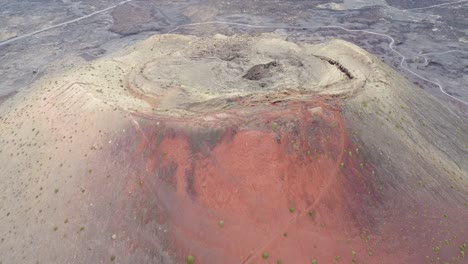 aerial drone footage of a huge red volcano and a solitary road in canary islands, spain